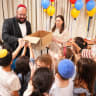 Rabbi Ephraim Duchman, Director of Development of Colel Chabad, distributing gifts to children as Mrs. Rochel Marton looks on.