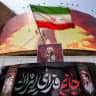 A man waves an Iranian flag before a political billboard at Valiasr Square in central Tehran on August 8, 2026. 