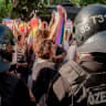Protesters hold up Pride flags as they stand in front of riot police officers in Izmir, Turkey, on June 27, 2026. 
