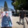 A young man holds an image of Beniyahu Razi who was murdered last month in Jerusalem, outside a court hearing on August 07, 2026.