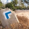 Blue and white trail marker painted on a stone shows the direction of travel along a hiking trail.