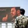 A Yemen's Houthi fighter stands next to a billboard depicting the Houthi leader Abdul-Malik al-Houthi during a demonstration staged to show solidarity with Iran on April 3, 2026 in Sana'a, Yemen.