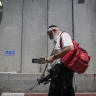 An ultra-Orthodox Jewish man carrying a gun and a first aid bag, walks by the Separation Wall at the entrance to the Jewish religious site of Rachel's Tomb, near Bethlehem, on June 26, 2014.