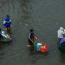 People carry groceries on shopping carts as they wade through a flooded street during heavy rain in Bangkok, Thailand, September 26, 2026.