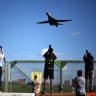 Plane spotters stand at a perimeter fence to see and photograph US Air Force (USAF) B-1 Lancer bomber jets taking off at RAF Fairford in south-west England on March 14, 2026. 