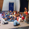 Jewish children gather around a teacher for an engaging Jewish educational event in a Synagogue