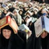 Shiite Muslim devotees sit in prayer while having copies of the Koran, Islam's holy book, placed on the head as they attend mass prayers.