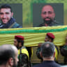 Men carry a coffin as they walk past images of Mohammad Mahdi Ammar, son of Hezbollah member of the Lebanese parliament Ali Ammar, and Abbas Fadel Yassin, who were killed amid the detonation of pagers across Lebanon, during their funeral in Beirut, Lebanon September 18, 2024.