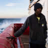 A migrant stands on the deck of rescue ship "Ocean Viking" operated by the NGO SOS Mediterranee as waves crash against the ship sailing in the Mediterranean Sea, near Italy, on January 2, 2026