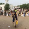 A girl carries a jerrycan as displaced people living in temporary shelters receive food aid in Al-Khawkhah, in Yemen's western Hodeidah province, on July 30, 2026.