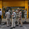 Police personnel stand outside a closed lab following an advisory from the local authority to close shops and other establishments at Connaught Place in New Delhi on July 23, 2026.