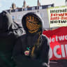 An anti Zionist protester stands in front of banners at Cable Street on October 4, 2026 in London, England on the 90th anniversary of the Battle of Cable Street.