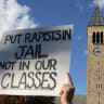 A demonstrator holds a placard as the McGraw Tower stands in the background during a Justice for Survivors rally at Cornell University in Ithaca, New York, US, October 5, 2026.