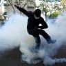 A masked student attempts to kick a tear gas canister, amid clashes with French riot police during a protest by French high school and university students near Lycee Paul Eluard high-school.