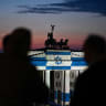People look at Berlin's landmark Brandenburg Gate is illuminated with the Israeli flag in Berlin on October 7, 2026, the third anniversary of Hamas's October 7 attack on Israel.