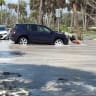 A man tries to push a car as waves wash over the road ahead of the arrival of Hurricane Isaias, in Englewood, Florida, US, October 9, 2026.