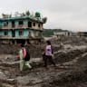 People walk past damaged houses following deadly flash floods and a mudslide in Devighat, Nuwakot district, Nepal, September 21, 2026. 