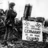 Corporal Urban Mayo from Ontario, Canada, watches the warning under the double swastikas on the border of German in the Canadian sector of the Western Front a few month before the end of World War II, February 14, 1945 
