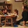 Family sitting on floor playing with girl around coffee table at home