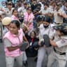 Security personnel and police detain a journalist during a protest by the Cockroach Janta Party (CJP) seeking the resignation of India's Chief Election Commissioner Gyanesh Kumar, near the protest site in New Delhi, India, October 11, 2026.