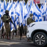 ISRAELI SECURITY forces stand outside a shop owned by Palestinian Mouayad Oweis after settlers placed dozens of Israeli flags, blocking access to the roadside business in the West Bank, in October 2026.