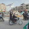DEMONSTRATORS RIDE through a street while waving Syrian flags during a rally in Hasakah, Syria, last Friday. 