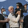 Hamas leader Yahya Sinwar holds the child of an Al-Qassam Brigades fighter, who was killed in the recent fighting with Israel, with a Kalashnikov rifle in his hand during a rally in Gaza City on May 24, 2021.