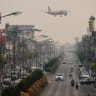 A passenger plane prepares to land at the airport as commuters drive on the road below on a heavily polluted day in Chiang Mai on April 2, 2026