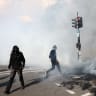 Masked protesters react through tear gas amid clashes with the French riot police during a demonstration , France, October 17, 2026.