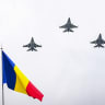 Three F-16 fighting jets of the Romanian Air Force fly over a Romanian flag during a military parade marking the National Day of Romania in Bucharest December 1, 2023.