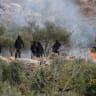 Israeli settlers next to a fire amid clashes with Palestinians during olive harvest in Abu Falah near Ramallah in the West Bank, October 16, 2026.