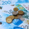 New Israeli shekel (NIS) banknotes and coins are seen on a table (illustrative)