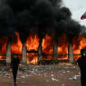 Protesters stand in front of Lyon’s tourism office set on fire during a demonstration to protest against the ‘high cost of living,’ in Lyon last week.