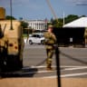 The White House is visible as National Guard troops stand next to a military Humvee along Constitution Avenue on August 12, 2026 in Washington, DC.