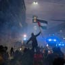 A demonstrator waves a Palestinian flag as protesters face police amid smoke during clashes following a protest against the rising cost of living in Bologna, Italy, October 17, 2026.