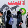 Women walk past a mural with the slogan "no to violence" (against women) drawn on the walls of a school in Syria's northern city of Manbij on December 21, 2024.
