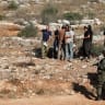 Israeli forces stand guard as Israeli settlers gather during the olive harvest at Palestinian-owned olive groves in Deir Abu Mashal, near Ramallah, in the West Bank, October 19, 2026. 