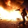 A man throws a plastic traffic cone through a burning barricade amid clashes during a day of demonstrations against the cost of living and rising fuel prices in Paris as part of nationwide protests called by the "Yellow Vests" movement, joined by French high school and university students, teachers 