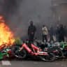 Masked protesters stand next to burning bicycles amid clashes during a demonstration against the cost of living and rising fuel prices near the Place de la Republique in Paris as part of nationwide protests called by the "Yellow Vests" movement, joined by French high school and university students, 