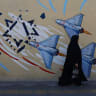An Iranian woman walks next to an anti-Israeli mural on a street in Tehran, Iran, May 18, 2026.