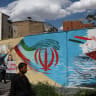 People walk on a street near a mural featuring an image of the late Supreme Leader of Iran, Ayatollah Ali Khamenei, in Tehran, Iran, May 18, 2026. 