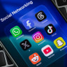 In this photo illustration, icons for WhatsApp, Facebook, Threads, X, Instagram, TikTok, Reddit, YouTube and Snapchat are displayed on a smartphone placed over computer keyboards on August 30, 2026