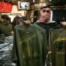 A shop assistant, who refused to be identified, displays T-shirts presenting the official logotype of radical Islamic Shiite group Hezbollah (L) and another of Lebanese Army´s special forces (R), on sale at an army and navy police supply shop, in Sao Paulo, Brazil, July 28, 2006.