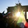 Protesters wave Iranian pre-Islamic revolution of 1979 and shout slogans during a demonstration in front of the Brandenburger Gate as the sun shines in Berlin, on March 1, 2026.