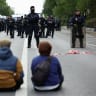 Demonstrators sit on the roadway in front of officers of the French CRS riot police during a protest organised by student collectives and trade unions in Paris, France, October 22, 2026