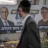 An ultra-Orthodox Jewish man walk near an electoral banner for the Reservist-Economic Party  led by Yoaz Hendel (R) and Yaron Zelekha (L) in Bnei Barak, near Tel Aviv, October 18, 2026