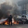 A French police officer extinguish burning bicycles during a demonstration against the cost of living and rising fuel prices in Paris, France, October 17, 2026.