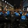 A woman faces riot police during clashes following a protest against the rising cost of living in Bologna, Italy, October 24, 2026.