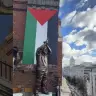 A statue of Marwan Barghouti next to a large Palestinian flag on top of Palestine House, London.