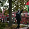 A pro-Palestinian supporter waves a Palestinian flag outside the venue for the World Academic Summit at The University of Manchester for a "Demonstration against British complicity and in honour of Palestinian martyrs", in central Manchester on October 7, 2024.